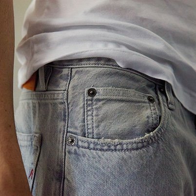 Nahaufnahme einer hellblauen Jeans mit weißem Oberteil und orangefarbenem Innenfutter.