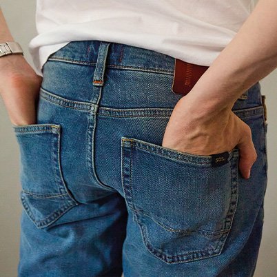 Detailaufnahme der Rückseite einer Person in blauen Jeans, wobei die Hände in den Hosentaschen stecken