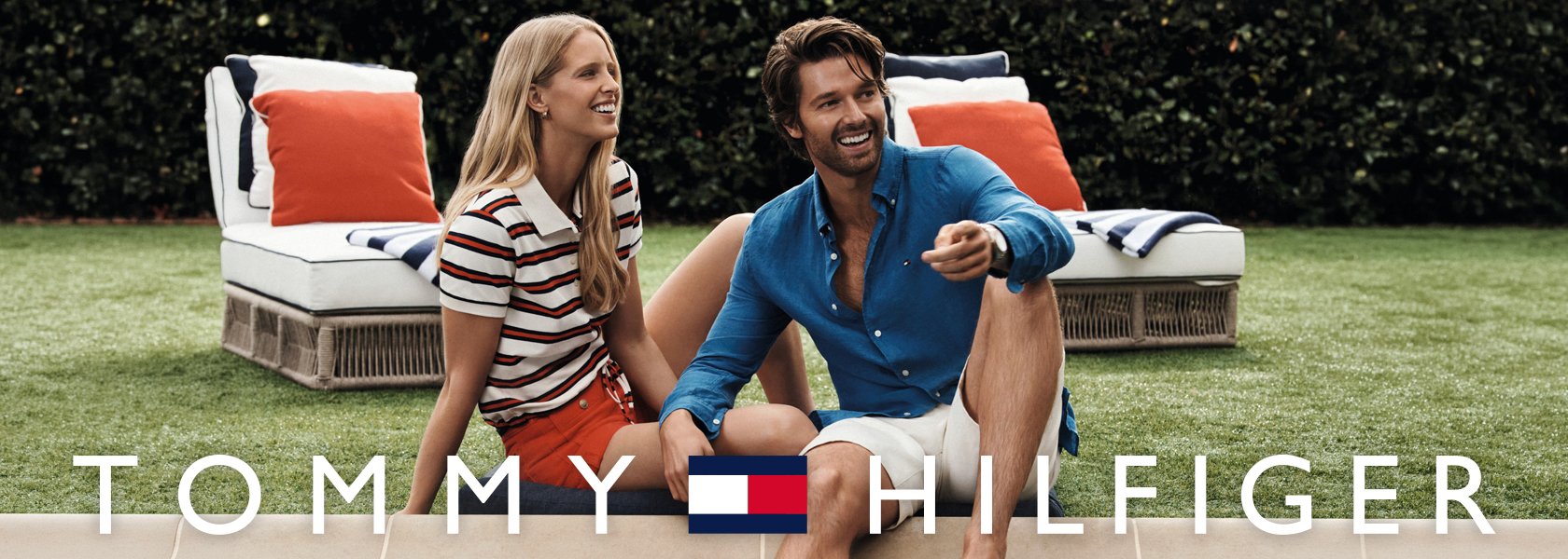 Mann und Frau lächeln entspannt im Garten, mit TOMMY HILFIGER Logo.