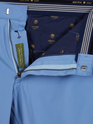 Nahaufnahme einer hellblauen Golfhose von Meyer Golf. Die Innenseite des Bunds zeigt ein dunkelblaues Futter mit wiederholtem Logo-Druck. Ein kleines Etikett mit Informationen zur Herstellung ist sichtbar.