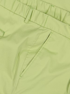 Close-up of light green pants, showing the waistband and a pocket detail. The fabric appears smooth and possibly woven. The image focuses on texture and color of the garment.