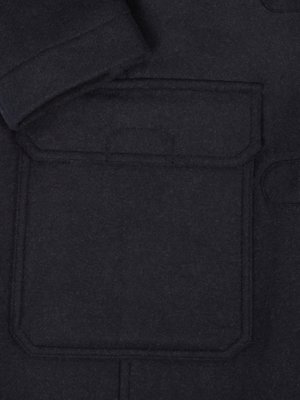 Close-up of a dark gray or black wool jacket showing a large, welted patch pocket. The pocket is stitched to the jacket. The fabric appears thick and textured.