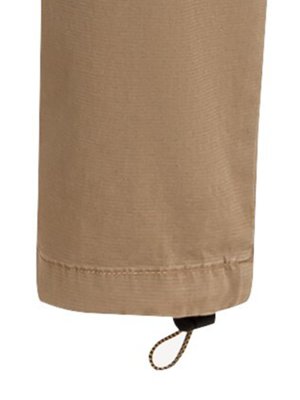Close-up of the bottom of a tan fabric garment. The hem is visible, with a drawstring and cord lock at the bottom. The cord is brown and the lock is black.