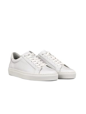 Two white leather sneakers with white laces are pictured against a white background. The sneakers are positioned at an angle, with the left shoe in front of the right. Both have a rounded toe and a thick white sole.