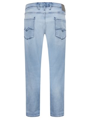 Helle Jeans von hinten. Der Bund hat Schlaufen und einen Lederaufnäher. Auf den Gesäßtaschen sind Ziernähte in Form einer Wellenlinie. Die Hose ist hellblau und leicht ausgewaschen.