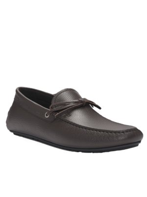 Ein einzelner, brauner Mokassin-Schuh, der auf weißem Hintergrund steht. Der Schuh hat eine runde Spitze und eine Schleife. Die Ledertextur ist sichtbar. Ein dunkelbraunes Innenfutter ist auch zu sehen.