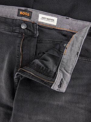 Draufsicht auf eine schwarze Jeanshose. Der Hosenlatz ist geöffnet und die Markenlogos BOSS und Soft Motion sind zu sehen. Knopf, Reißverschluss und Details der Innenseite sind erkennbar.