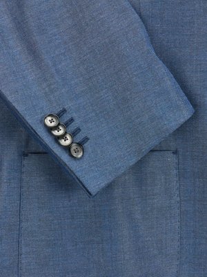 Close-up of a blue blazer sleeve. Four dark buttons are visible on the sleeve cuff, and a small pocket is partially visible. The fabric texture of the blazer appears textured.