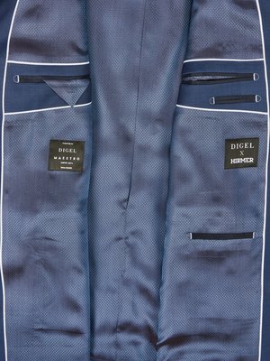 Inside of a blue suit jacket with two visible pockets, one with a small triangle of fabric. The interior lining is patterned. There is a label that says DIGEL Maestro and one that says DIGEL x HIRMER.