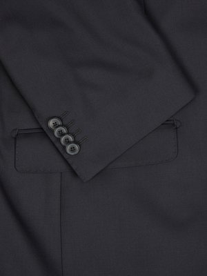 Close-up image shows a dark, possibly navy, suit jacket's sleeve and pocket. Four buttons are aligned on the sleeve. The pocket is visible below the buttons. The fabric has a smooth texture.