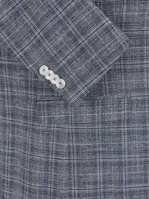 Detail saka tmavě modrého saka se čtvercovým vzorem, bílými knoflíky.  Sako má kostkovaný vzor v odstínech šedé a tmavě modré.  Jsou vidět čtyři bílé knoflíky.