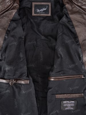 Interior view of a brown leather jacket, showing the inside lining and pockets. The lining is black with a repeated brand name. A label reads "Vegetable Tanned". There are two visible pockets, one with a button closure and one with a zipper.