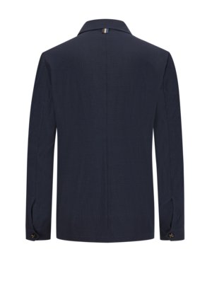 Rear view of a navy blue blazer. The blazer has long sleeves, a collared neckline, and two buttoned sleeve cuffs. A small striped detail is on the back of the collar. The fabric has a textured pattern.