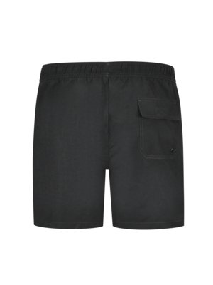Ansicht von hinten einer schwarzen Badeshorts auf weißem Hintergrund. Die Shorts haben einen Gummibund und eine aufgesetzte Gesäßtasche auf der rechten Seite. Am unteren Ende der Tasche befindet sich ein kleines Loch.