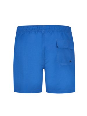 Back view of blue swim shorts. The shorts have an elastic waistband, a small pocket on the right side, and a small, dark button detail below the pocket. The shorts are solid blue.