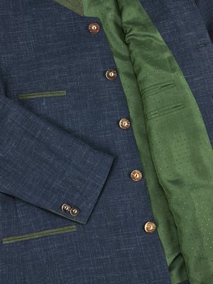 Dunkelblaues Jackett mit grünen Einfassungen und Knöpfen aus Holz. Das Innenfutter ist grün mit weißen Punkten. Der Kragen und die Innenseite der Jacke sind sichtbar. Zwei Knöpfe an der Manschette.