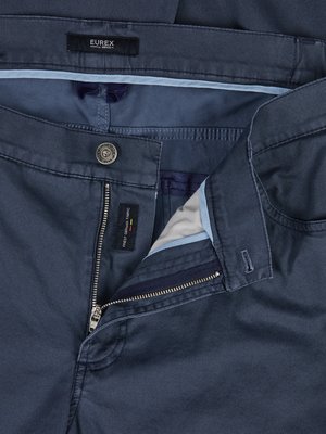 Detailaufnahme einer geöffneten, dunkelblauen Hose. Die Hose ist am Bund mit einem Knopf und einem Reißverschluss versehen. Auf dem Bund befindet sich ein Eurex-Etikett. Ein kleines Etikett mit "Finest German Fabric" ist am Reißverschluss sichtbar.