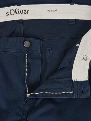 Close-up of navy blue pants with open zipper. The brand name "s.Oliver" and "Relaxed" are visible on a white interior label. The size W42 L32 is displayed on the interior. A metal button and a silver zipper are visible.