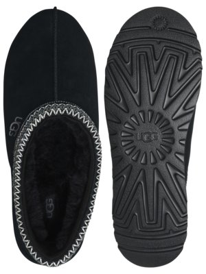 Two black UGG slippers are shown. The left slipper displays the top view, with a black exterior and white stitching along the edge. The right slipper reveals the bottom with a textured black sole. Both show the UGG logo.
