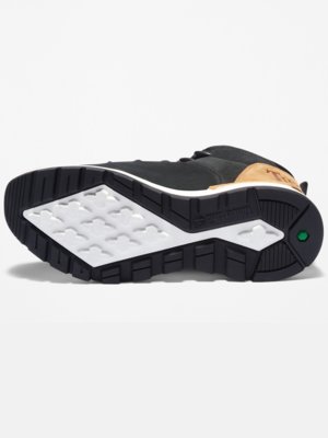 Widok od spodu czarnego buta sportowego. Podeszwa z czarnej gumy z białym rombem po środku. Po bokach podeszwy czarne i białe elementy. Widoczne logo Timberland i zielone logo.