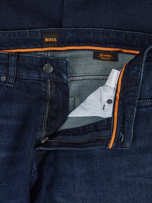 Dunkelblaue Jeans von BOSS. Die Hose ist geöffnet, so dass der Reißverschluss, der Knopf und das Innenfutter zu sehen sind. Orangefarbene Akzente sind an der Innenseite und am Bund zu sehen. Auf einem Etikett steht "REMAINE REGULAR FIT".