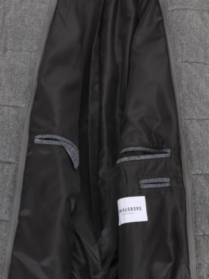 Close-up of a gray coat interior. The inner lining is black, with two pockets on the right side and one on the left. A white label with "RNRUSBORG" is visible. The coat is open.