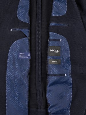 Nahaufnahme des Innenfutters eines dunkelblauen Sakkos. Links ein Etikett mit der Aufschrift "ZIGNONE" und rechts ein Etikett "DIGEL". Das Futter hat ein Muster aus Buchstaben. Drei kleine Taschen sind sichtbar.