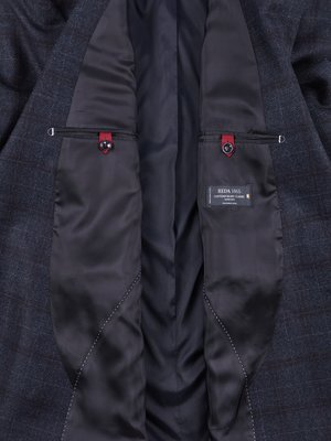 Interior of a gray plaid blazer. The lining is black with two pockets visible, each with a red button. A tag in the lower right pocket says REDA 1865 Contemporary Classic.