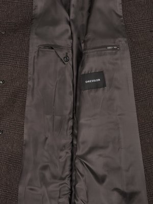 Close-up view of the inside of a brown plaid jacket, showing two pockets and a black DRESSLER label.