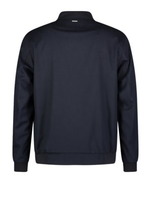 Ansicht einer marineblauen Jacke von hinten. Die Jacke hat einen Stehkragen mit einem kleinen Detail. Der untere Saum und die Manschetten sind elastisch. Die Ärmel sind lang.