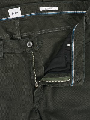Close-up of olive green pants partially unbuttoned. The zipper is open, revealing the inside of the pants. A button is visible on the waistband. Brax and Style Chuck labels are sewn on.