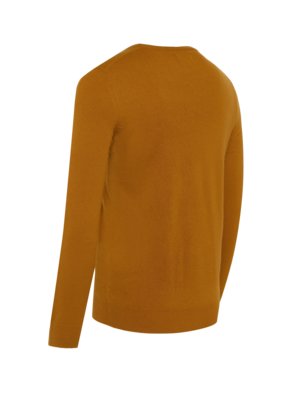 Ein ockerfarbener Pullover mit langen Ärmeln, der von hinten leicht schräg abgebildet ist. Der Pullover ist aus Strickstoff, mit Rundhalsausschnitt. Der Hintergrund ist weiß.