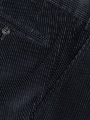 Nahaufnahme von dunkelblauem Cordstoff. Zu sehen sind vertikale Rippen, eine Gesäßtasche mit eingenähtem Knopf und weitere Stoffpartien, die Falten bilden. Der Stoff hat eine matte Oberfläche.
