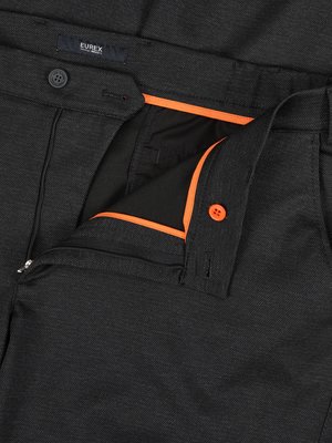 Nahaufnahme einer geöffneten schwarzen Hose. Der Hosenschlitz ist offen, dahinter ist ein orangefarbener Saum zu sehen. Ein Knopf ist zu sehen. Auf dem Bund ist "EUREX" auf einem Etikett aufgedruckt.