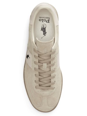 Ein beigefarbener Sneaker von Polo Ralph Lauren, von oben fotografiert. Der Schuh hat eine beige Schnürsenkel, eine weiße Zunge und ein seitliches Logo. Innen befindet sich das Polo Logo.