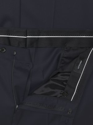 Close-up of dark navy trousers showing the waistband, zipper, button closure, and a black label with white text that reads DRESSLER.
