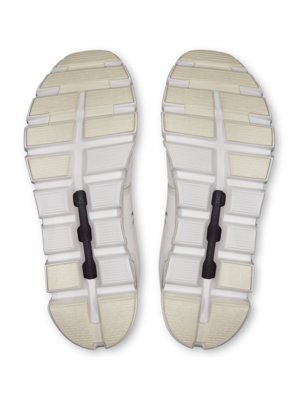 Nahaufnahme der Sohlen zweier weißer Laufschuhe mit detailliertem Gummi-Profil und schwarzen Stoßdämpfern