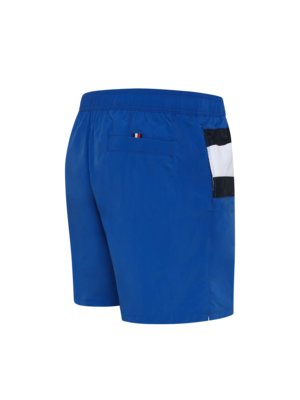 Blaue Badeshorts mit weiß-schwarzem Streifenmuster an der Seite und einer kleinen Tommy Hilfiger Flagge auf der Rückentasche.