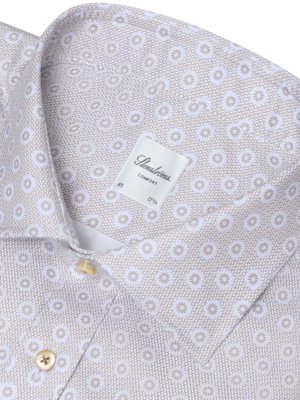 Close-up view of a collared shirt. The shirt is light brown with a white floral pattern. A label reads "Stenströms Comfort" with size information. The shirt has a buttoned collar and two buttons visible.