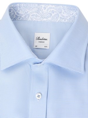 Close up of a light blue patterned dress shirt with a white button and a Stensroms brand label.