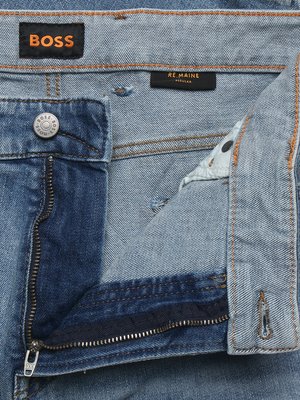 Detailaufnahme eines offenen Reißverschlusses an einer blauen Jeans mit sichtbarem BOSS-Logo und einem Etikett RE.MAINE REGULAR