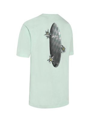 A light green t-shirt with a graphic of a gray surfboard surrounded by white flowers on the back.