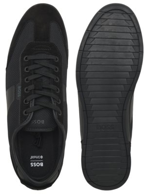 Para czarnych sneakersów marki BOSS widziane z góry i podeszwa od drugiego buta z widocznym bieżnikiem.