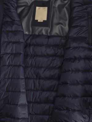 Close-up view of the interior of a dark navy puffer jacket with horizontal quilted sections and a grey lining.