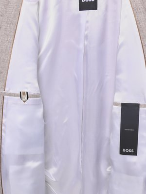 Blick in das Futter eines Blazers, innen weiß gefüttert, mit zwei BOSS-Etiketten, davon eines mit "ITALIAN FABRIC".