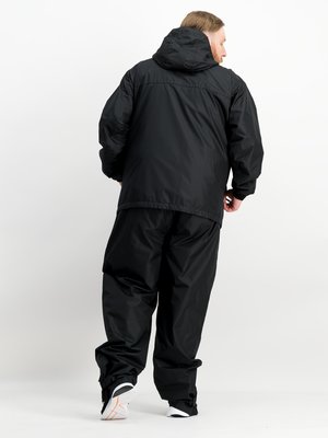 A person wearing a black rain suit with a hood stands with their back to the camera. The suit includes a jacket and pants. The person is wearing white and black shoes with an orange accent. The background is white.