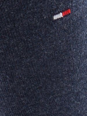 Nahaufnahme eines dunkelblauen Stoffes. Oben rechts befindet sich ein kleines Emblem aus weißen, roten und blauen Streifen. Der Stoff hat eine feine, ungleichmäßige Struktur.