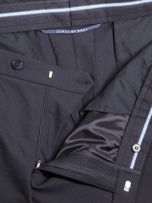 Nahaufnahme einer Hose aus dunklem Stoff. Reißverschluss, Knopf und Hosenbund sind sichtbar. Innenfutter aus glänzendem, schwarzem Material. Blauer Streifen mit weißem Muster auf der Hose.