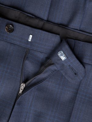 Nahaufnahme einer geöffneten, blauen Stoffhose. Der Reißverschluss ist geöffnet, oberhalb befindet sich ein Knopf und ein Metallhaken. Detailaufnahme zeigt das karierte Gewebe des Hosenstoffs.
