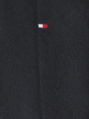Ein Nahaufnahmbild zeigt einen dunkelblauen Stoff mit einem kleinen, rechteckigen Logo aus rot, weiß und blau. Der Stoff hat eine gerippte Textur. Das Logo ist klein und horizontal.